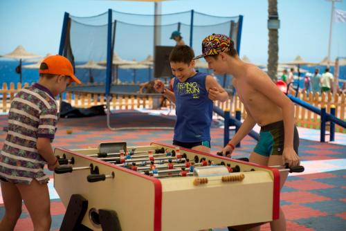 three boys playing with a foosball table at the beach at Amphoras Beach - Ultra All Inclusive in Sharm El Sheikh