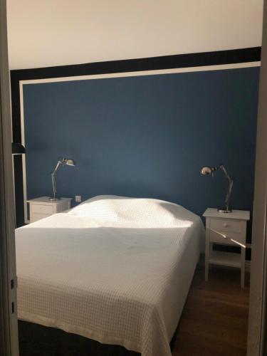 a bedroom with a blue wall and a bed with two tables at Appart 2 pièces avec parking QUARTIER DU LAC in Saint-Jean-de-Luz