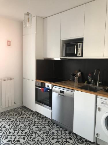 a kitchen with white cabinets and a sink and a dishwasher at Appart 2 pièces avec parking QUARTIER DU LAC in Saint-Jean-de-Luz