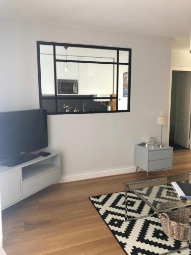 a living room with a flat screen tv and a table at Appart 2 pièces avec parking QUARTIER DU LAC in Saint-Jean-de-Luz