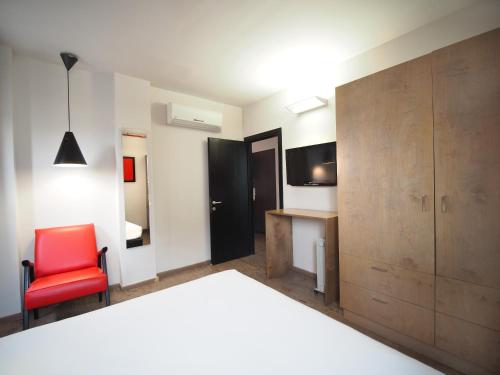 a bedroom with a bed and a red chair at Ben Yehuda Apartments in Tel Aviv
