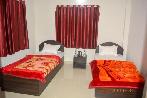 two beds in a room with red curtains at Gaurav guest house in Bodh Gaya