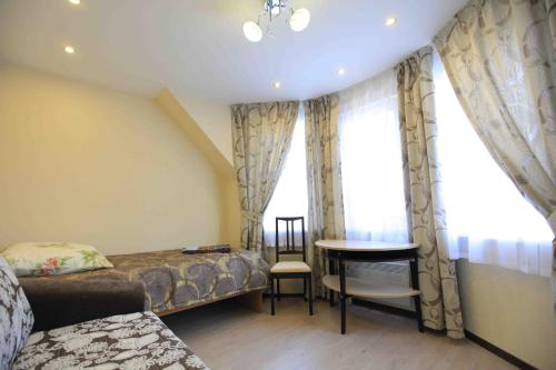 a bedroom with a bed and a table and window at Guest House on Vokzalnaya in Nyandoma