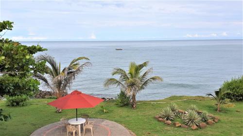 a table with a red umbrella next to the ocean at Cabaña PEDREGAL in Puerto Escondido