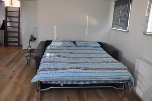 a bed with a striped blanket on it in a room at Private Lodge on Houseboat Amsterdam in Amsterdam