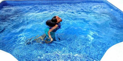 a woman is in a pool of blue water at El Conde de Villa Rosa in Salado