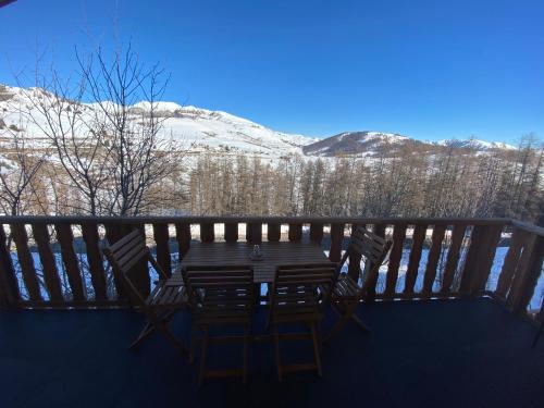 a table and chairs on a deck with snow covered mountains at Haut de Chalet L'entasse n°9 in Valberg