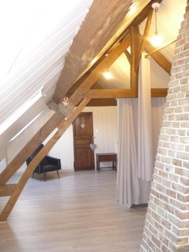 an attic with wooden beams and a room with a door at L'ESCALE in Camps-en-Amiénois