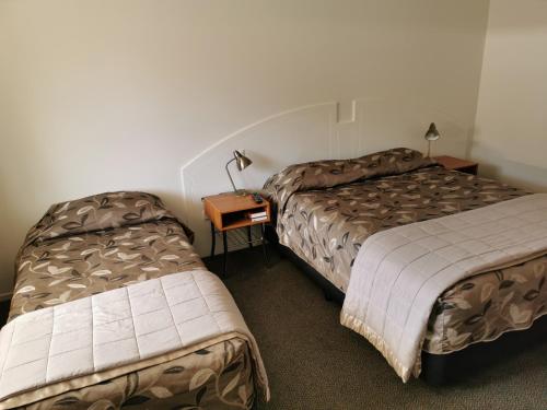 a hotel room with two beds and a table at Bks Egmont Motor Lodge in New Plymouth