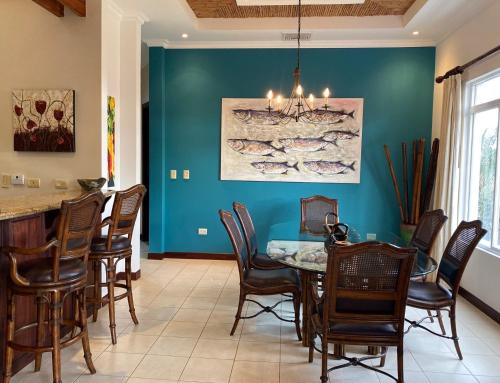 a dining room with a blue wall and a table and chairs at Palm Coast Luxury Rentals in Esterillos Este