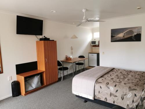 a bedroom with a bed and a desk and a television at Bks Egmont Motor Lodge in New Plymouth