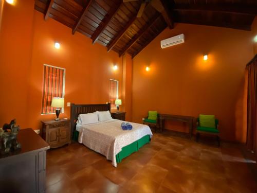 a bedroom with a bed and two green chairs at Palm Coast Luxury Rentals in Esterillos Este