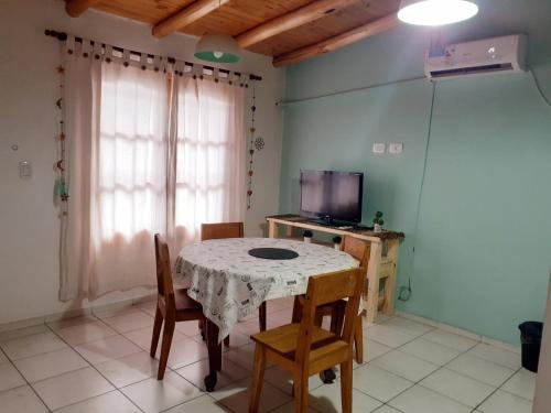 une salle à manger avec une table, des chaises et une télévision dans l'établissement Departamentos Pequeña Ramona, à San Rafael