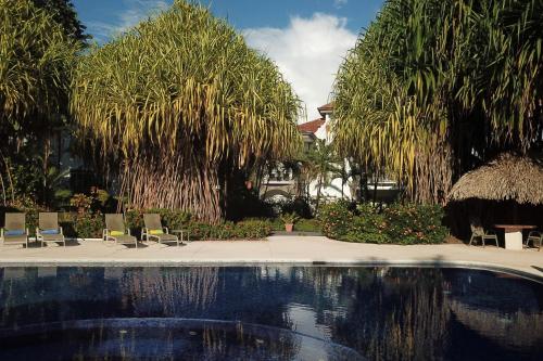 a swimming pool in a yard with chairs and trees at Palm Coast Luxury Rentals in Esterillos Este