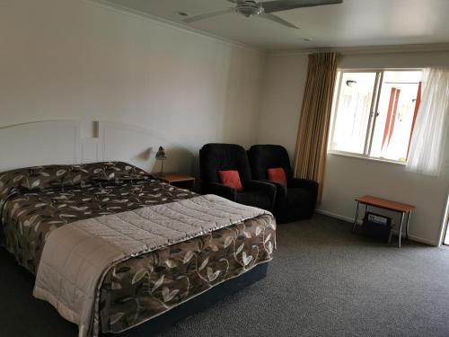 a hotel room with a bed and two chairs at Bks Egmont Motor Lodge in New Plymouth