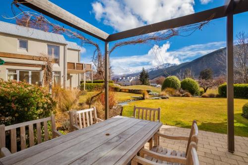 a picnic table on a patio with mountains in the background at Millbrook Resort in Arrowtown