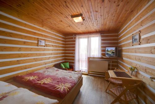 Habitación con cama y escritorio en una habitación de madera. en Pension H, en Jáchymov