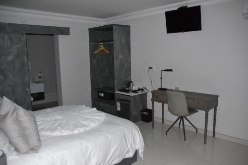 a bedroom with a bed and a desk and a computer at Prisatt Boutique Hotel in Onverwacht