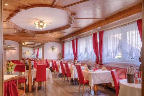 een eetkamer met tafels en rode stoelen bij Hotel Italia in Canazei