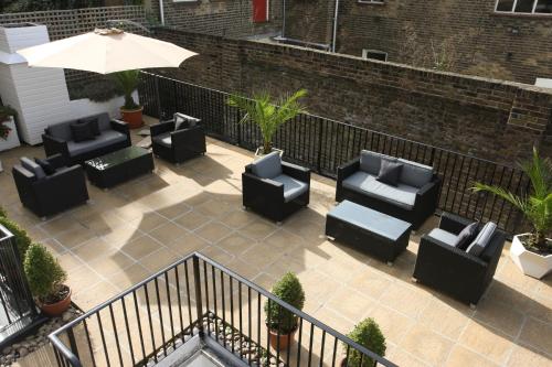 a patio with black chairs and an umbrella at New Linden Hotel in London