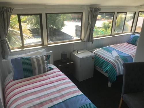 a room with two beds and two windows at Sandy Feet Lodge in Christchurch