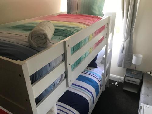 a white bunk bed with colorful sheets on it at Sandy Feet Lodge in Christchurch