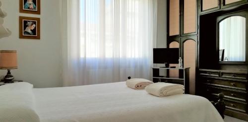 een slaapkamer met een bed met witte lakens en een raam bij L'alloggio di Anna Maria. Camera con bagno privato in Empoli