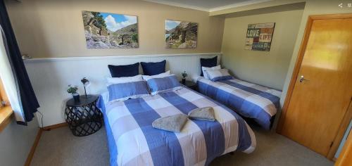 a bedroom with two beds with blue and white sheets at Roxburgh Clutha Gold TOP 10 Holiday Park in Roxburgh