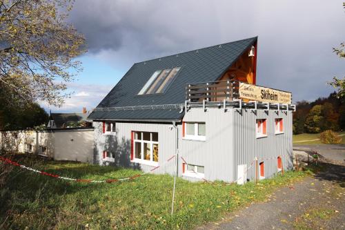 a small white house with a black roof at FeWo Skiheim in Großschönau