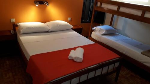 two beds in a room with two white slippers at Hotel Vanderloo in Posadas