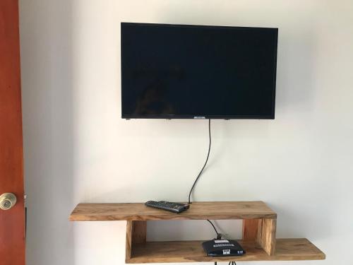 a flat screen tv on a wooden stand with a remote control at ANCHORAGE INN Moalboal in Moalboal