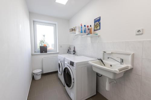 a white bathroom with a washing machine and a sink at FeWo Skiheim in Großschönau