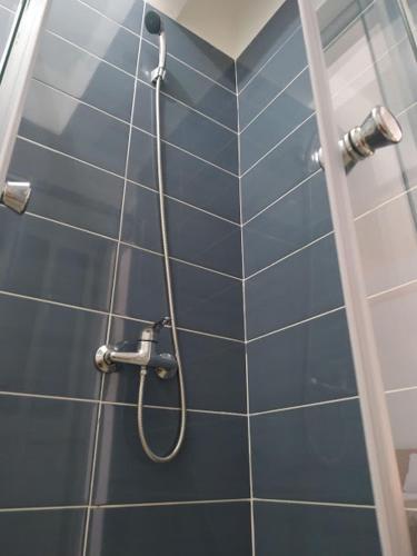 a shower with a hose on a blue tiled wall at Plateau Bedroom & Chambre - Praia Center 1 in Praia