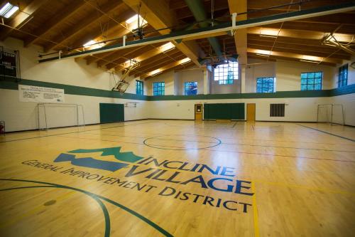 a gym with a basketball court with a orange village management district sign on the floor at The Cozy Downtime Condo in Incline Village