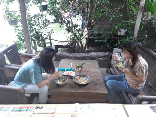 two women sitting at a table with bowls of food at Arjuna Garden Homestay in Yogyakarta
