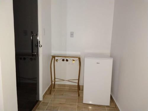 a white kitchen with a refrigerator and a table at Pousada Solar Encanto do Marajó in Soure