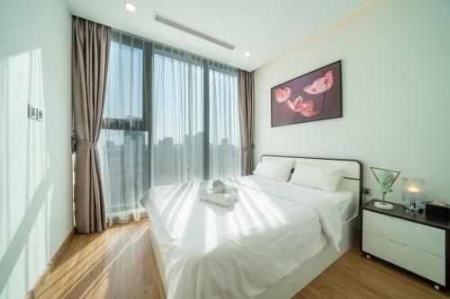 a bedroom with a large white bed and a large window at Vinhomes Metropolis Hanoi - CitiHome in Hanoi