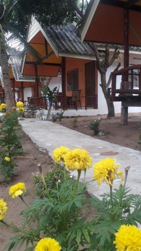 a group of yellow flowers in front of a building at Long Beach Garden Resort in Ko Lanta