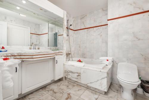 a white bathroom with a toilet and a tub and a sink at Sint Maarten Blue Dream 1BR (C) in Cupecoy