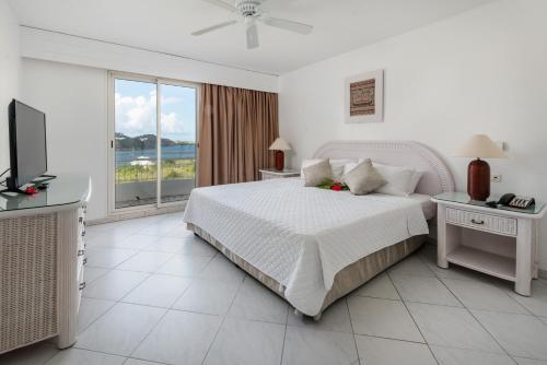 a white bedroom with a bed and a television at Sint Maarten Blue Dream 1BR (C) in Cupecoy