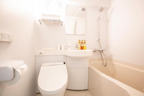 a white bathroom with a toilet and a sink at HOTEL MYSTAYS Higashi Ikebukuro in Tokyo