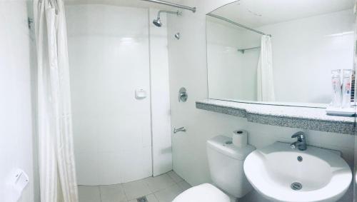 a bathroom with a toilet and a sink and a mirror at Maharajah Hotel in Angeles