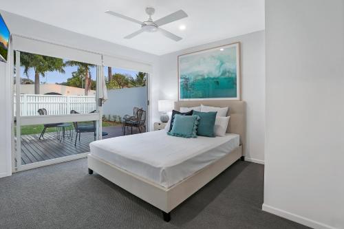 a white bedroom with a bed and a balcony at Walk to Hastings Street, Noosa Sound in Noosa Heads