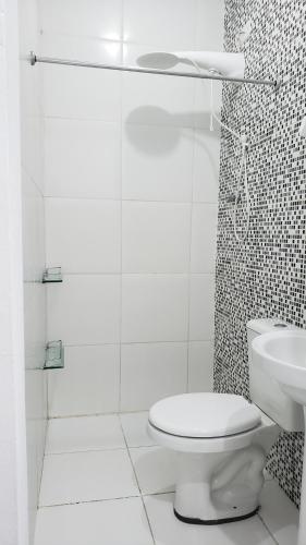 une salle de bains blanche avec toilettes et lavabo dans l'établissement Apto Térreo em Tramandaí, à Tramandaí