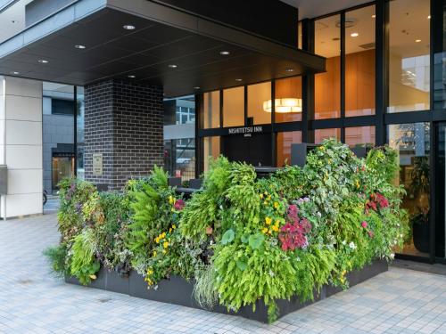 eine Reihe von Pflanzen vor einem Gebäude in der Unterkunft Nishitetsu Inn Fukuoka in Fukuoka