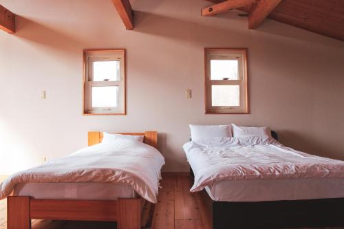 two beds in a room with two windows at Guest House ONLY ONE in Niseko