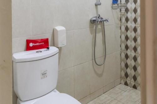 a bathroom with a toilet with a red bag on it at RedDoorz Plus near Tambun Station in Bekasi