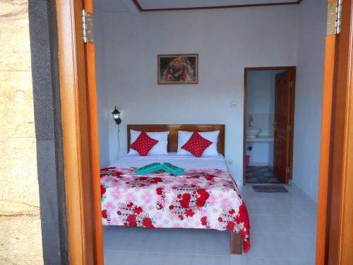 a bedroom with a bed with a red and white comforter at Ming Homestay in Sidemen