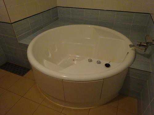 y baño con bañera blanca y pared de azulejos. en HOTEL Rplus Higashimatsuyama en Namegawa