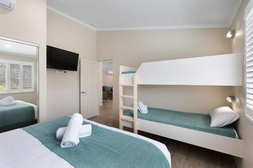 a bedroom with two bunk beds and a flat screen tv at BIG4 Adventure Whitsunday Resort in Airlie Beach